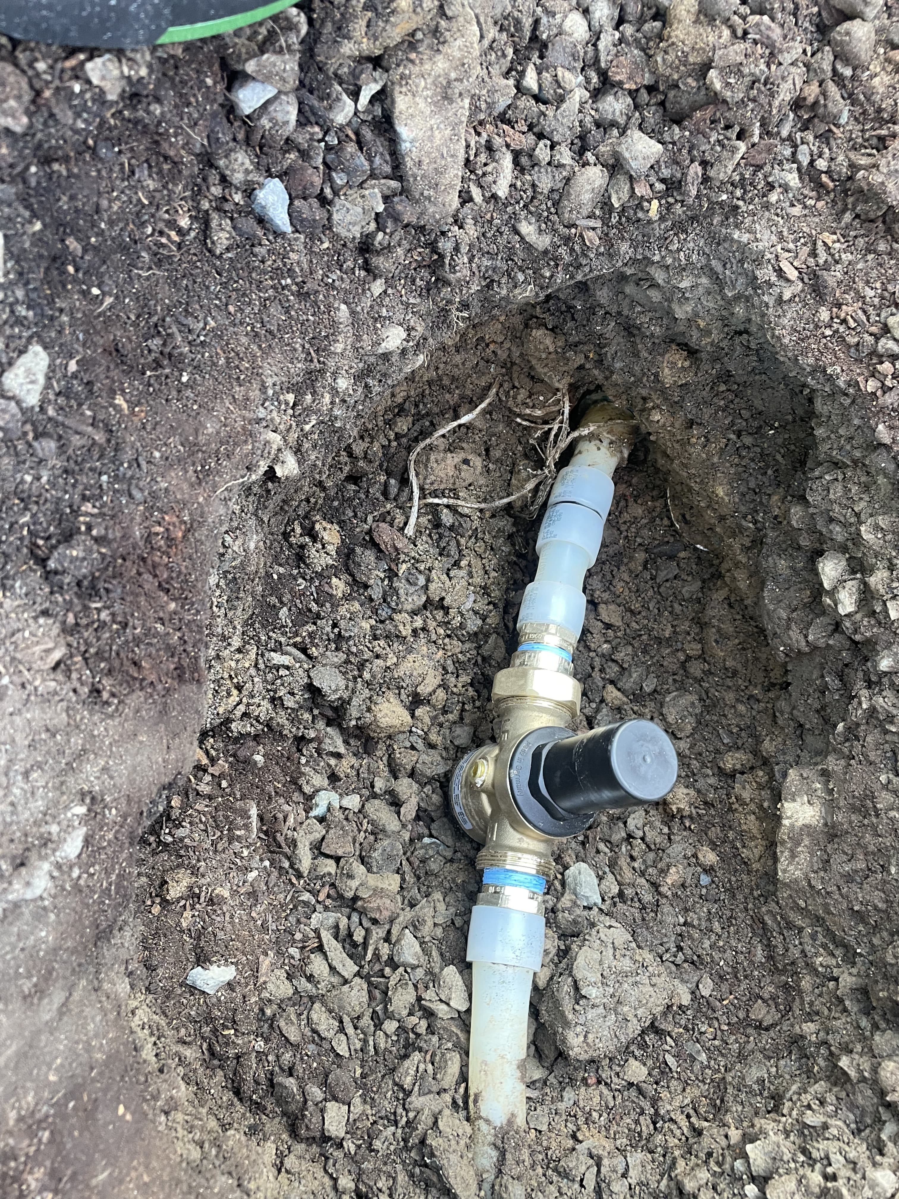 Close-up of an installed underground pressure regulator and connected pipework photographed by Table Rock Plumbing Solutions